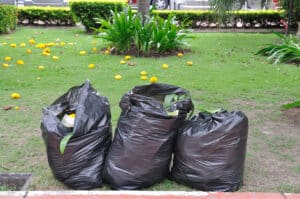 3 Black garbage bags on green yard in garden